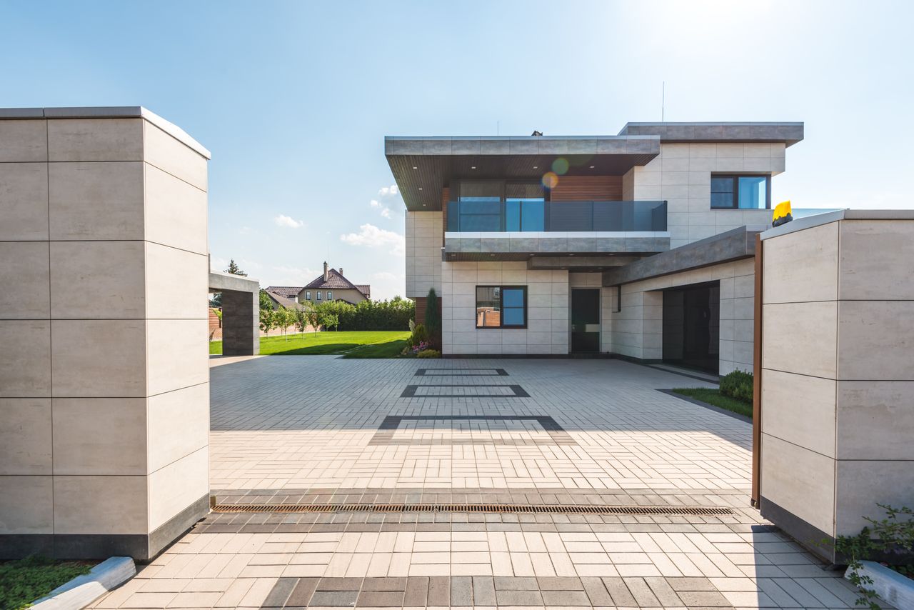 about-02 Contemporary two-story luxury home with spacious paved driveway and garden.